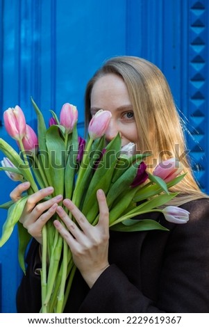 beautiful woman with long blond hair holding a bouquet of colorful tulips in her hands