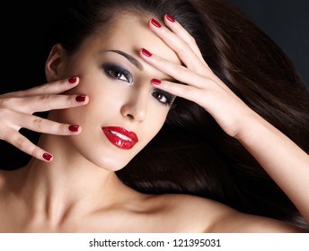 Beautiful Woman With Long Brown Straight Hairs And Red Nails Lying On The Dark Background