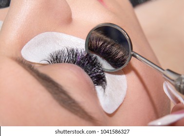 Beautiful Woman With Long Eyelashes In A Beauty Salon Eyelash Extension Procedure Lashes Close Up Shwoed In A Round Mirror. Focus On Eyelashes Reflection In The Mirror. Horizontal Image