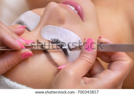 Beautiful Woman with long eyelashes in a beauty salon. Eyelash extension procedure. Lashes close up Foto stock © 