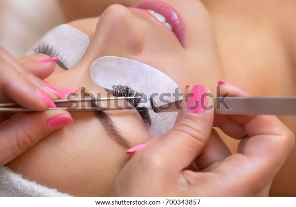 Beautiful Woman with long\
eyelashes in a beauty salon. Eyelash extension procedure. Lashes\
close up