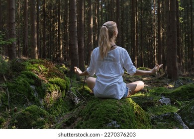 Beautiful woman with long hair sitting alone in green forest enjoys the silence and beauty of nature and meditation. - Powered by Shutterstock