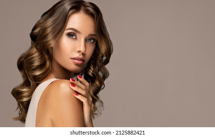 Schöne Frau mit langer und   glänzendes, gewelltes Haar.  Schönheitsmädchen mit Nagel-Frisur und roten Manikürnageln 