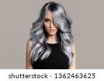 Beautiful woman with long wavy coloring hair. Flat gray background.