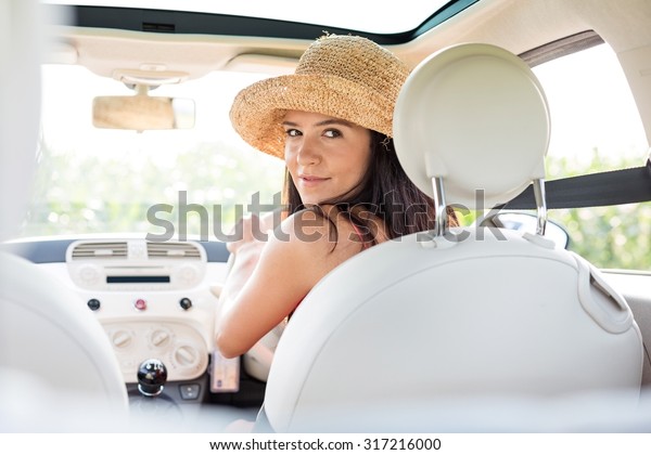 Beautiful woman\
looking back while driving\
car
