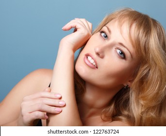 beautiful woman looking at camera, mid adult female face and hands, isolated on blue background