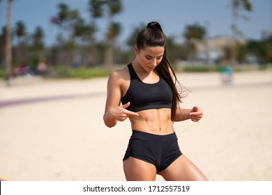 Beautiful Woman Looking Down At Her Firm Stomach And Muscular Abs Results Of Exercising And Training Hard In The Gym.