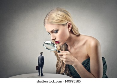 beautiful woman looking little man with magnifying glass