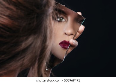 Beautiful woman looking in the piece of mirror