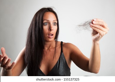 Beautiful woman is looking shocked at her hairbrush