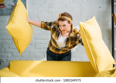 Beautiful Woman Looking Under Yellow Cushions At Home