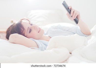 Beautiful woman lying in bed watching television