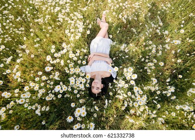 Beautiful Woman Lying Down In Daisy Field