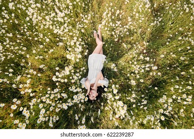 Beautiful Woman Lying Down In Daisy Field