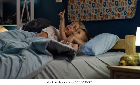 Beautiful Woman Lying With Little Boy In Bed And Telling Interesting Story Before Going To Sleep At Night