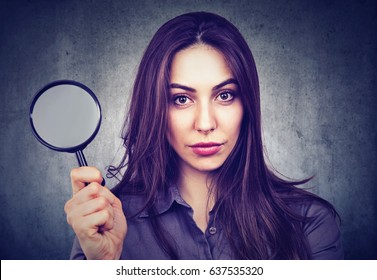 Beautiful woman with magnifying glass isolated on gray wall background.