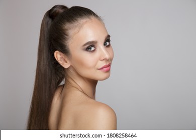 Beautiful Woman With Makeup On A Gray Background. High Ponytail And Long Hair. Copycpase