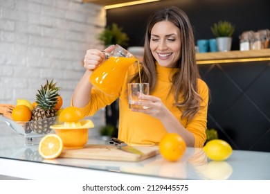 Beautiful woman making orange juice. Healthy eating lifestyle concept portrait of beautiful young woman preparing juice at home in kitchen.