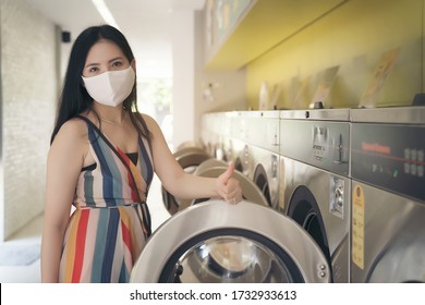 Beautiful woman with mask doing laundry at laundromat shop. - Powered by Shutterstock