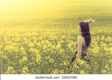 Beautiful Woman In Meadow Of Yellow Flowers From Side Behind. Attractive Genuine Young Girl Enjoying The Warm Summer Sun In A Wide Green And Yellow Meadow. Part Of Series.