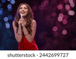 Beautiful woman with microphone singing on stage in color lighted smoke