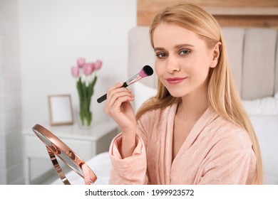 Beautiful Woman With Mirror Applying Makeup In Bedroom