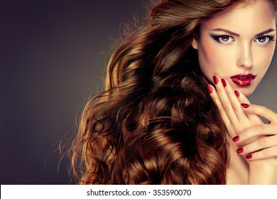 Beautiful woman model with long curly hair . fashion trend image ,the girl with blue eyes ,  makeup and hairstyle curls. Red nail manicure