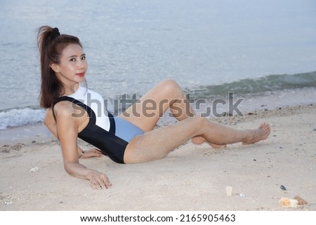 Beautiful woman model in white swimsuit posing on the beach,golden hour,leisure activities.