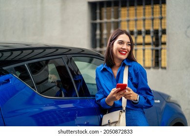 Beautiful Woman Next To Blue Car Using And Looking At Cell Phone