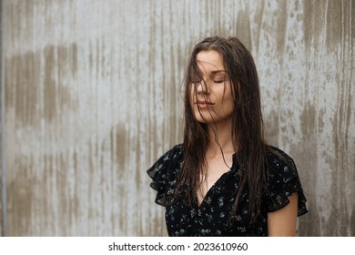 Beautiful woman next to the concrete wall. Daily energy in city. Mental health in modern lifestyle. Rainy day and wet hair. How to find inter peace from work stress and disorder. Meditation outdoors