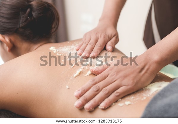 Beautiful woman njoying a salt\
scrub massage and having exfoliation treatment in spa room.\
Brunette getting a salt scrub beauty treatment in the health spa.\
Body Scrub.
