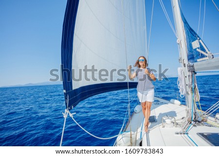 Beautiful woman on board of sailing yacht on summer cruise. Travel adventure, yachting on the summer vacation in Greece. Woman clothing in sailor style, nautical fashion.