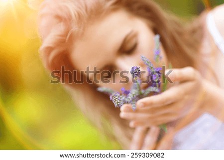 Beautiful woman on meadow holding lavender in her hands.