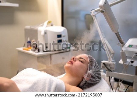 Beautiful woman on ozone therapy with facial steamer in beauty salon.