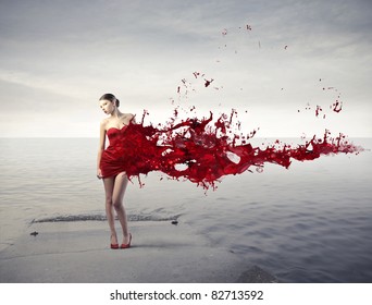 Beautiful woman on a pier with her dress melting in red paint