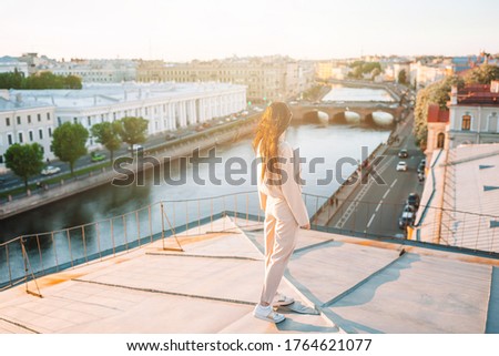 Beautiful woman on rooftop enjoying with view of beautiful sunset in Saint Petersburg in Russia