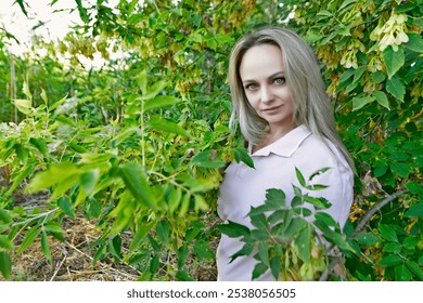 A beautiful woman on the shore of a lake in the branches and clusters of elderberries. - Powered by Shutterstock