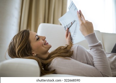 Beautiful Woman On A Sofa Reading A Paper In A Well Lit Stylish  Living Room