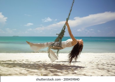 Beautiful Woman On A Swing On The Beach