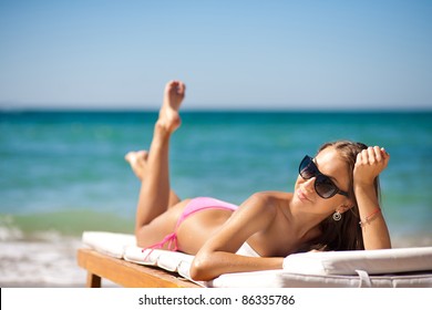 beautiful woman on a tropical beach on a chaise lounge