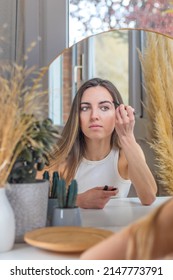 Beautiful Woman Painting Her Eyebrows While Putting On Makeup In Her Vanity