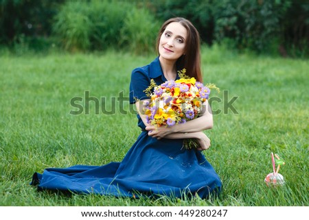 beautiful woman in a park on the grass with a bouquet of flowers 