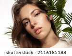 Beautiful woman with perfect  skin and natural make-up holding tropical   leaves