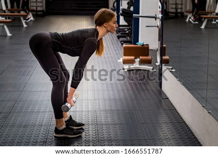 Beautiful woman performs Romanian deadlift in gym
