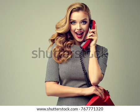 Beautiful woman in pin up style with vintage red phone.  Shocked  and happy pretty girl  . Presenting your product. Expressive facial expressions