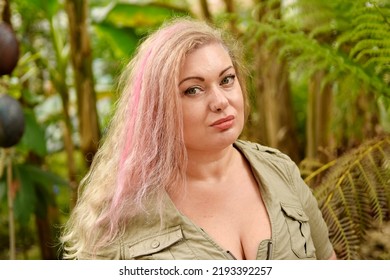 Beautiful Woman With Pink Hair Posing In Tropical Garden Standing  Wearing Dress Looking Away . Sexy Girl Nice Make Up Glamour Photography Outdoors