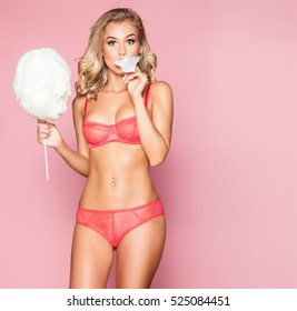 Beautiful woman in pink lingerie on a pink background with cotton candy