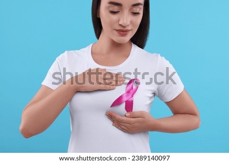 Beautiful woman with pink ribbon on light blue background. Breast cancer awareness