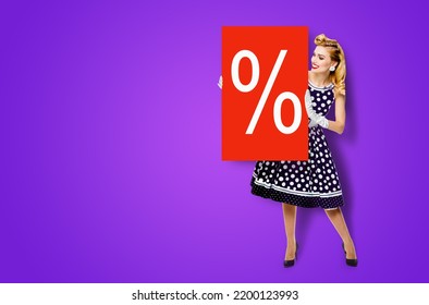 Beautiful Woman In Pinup Dress Holding, Showing Red Board With Procents % Sign. Full Body Pin Up Girl With Advertising Offer, Isolated On Violet Purple Background. Sales, Discounts Rebates Ad Concept.