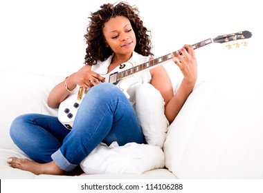 Beautiful woman playing guitar and relaxing at home - Powered by Shutterstock